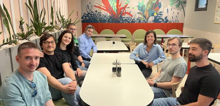 Members of Absci's Belgrade team seated around a table in a colorful office.